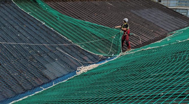 Workmen installing roof over netting